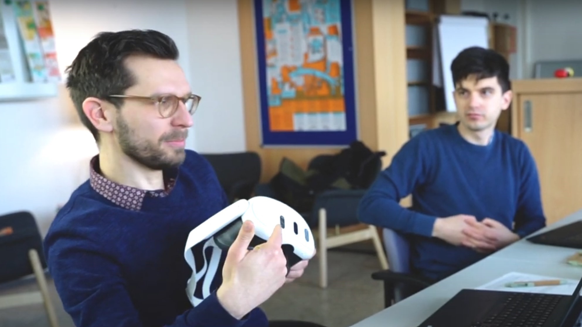 A young man explains something while pointing at augmented reality glasses.